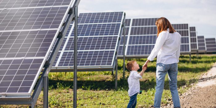 mãe e filho andando ao lado de painéis solares de kit energia solar
