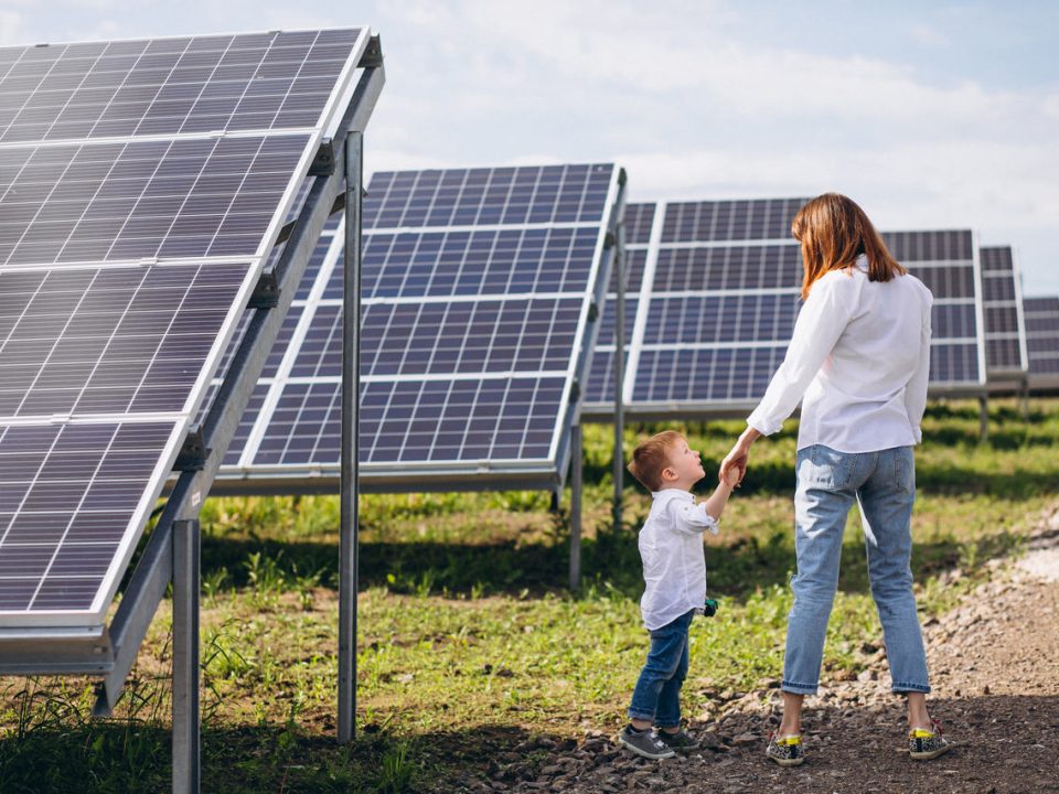 mãe e filho andando ao lado de painéis solares de kit energia solar